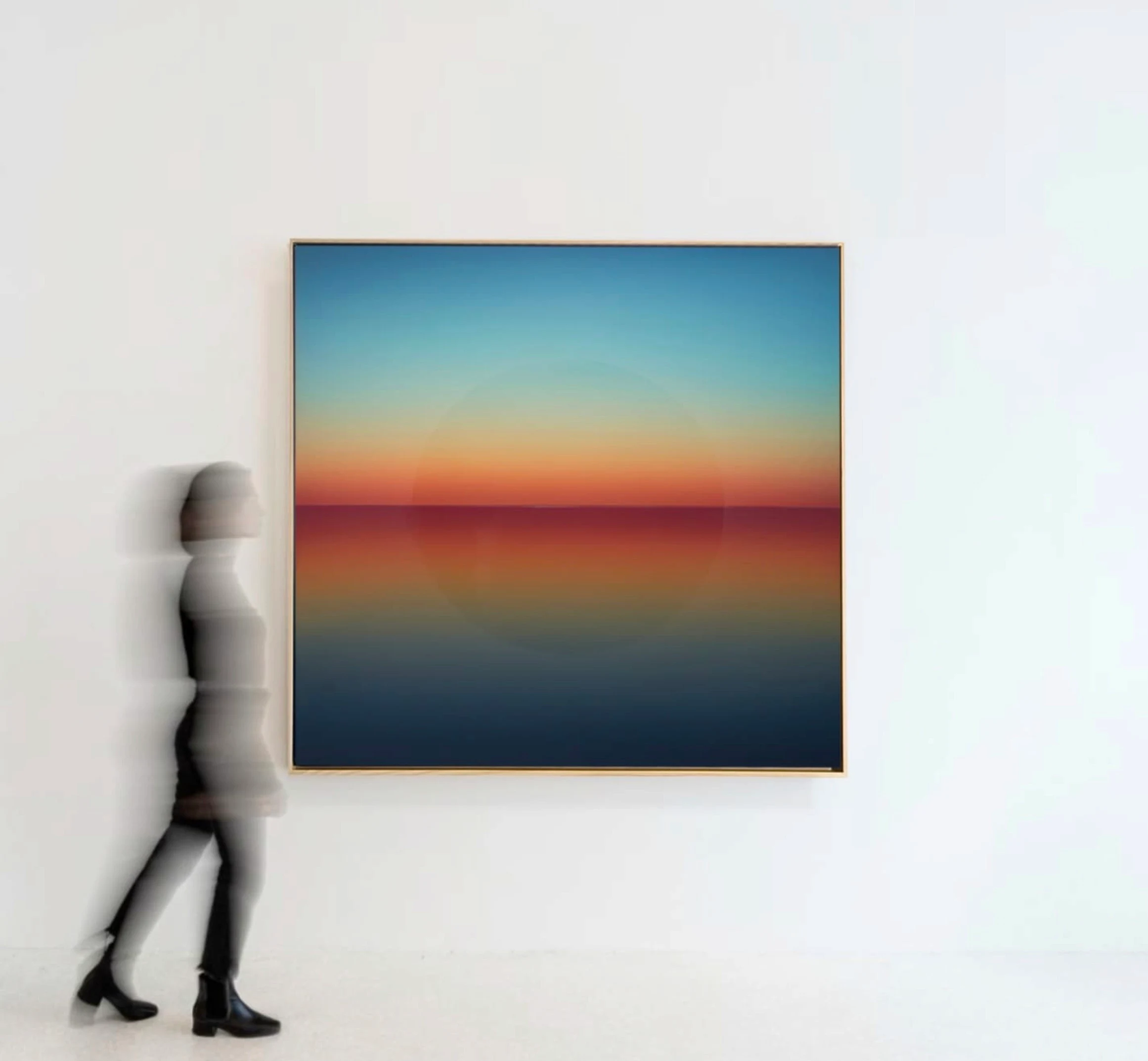 A square painting banded from blue sky through an orange and red horizon into dark water; a figure walks past, blurred.