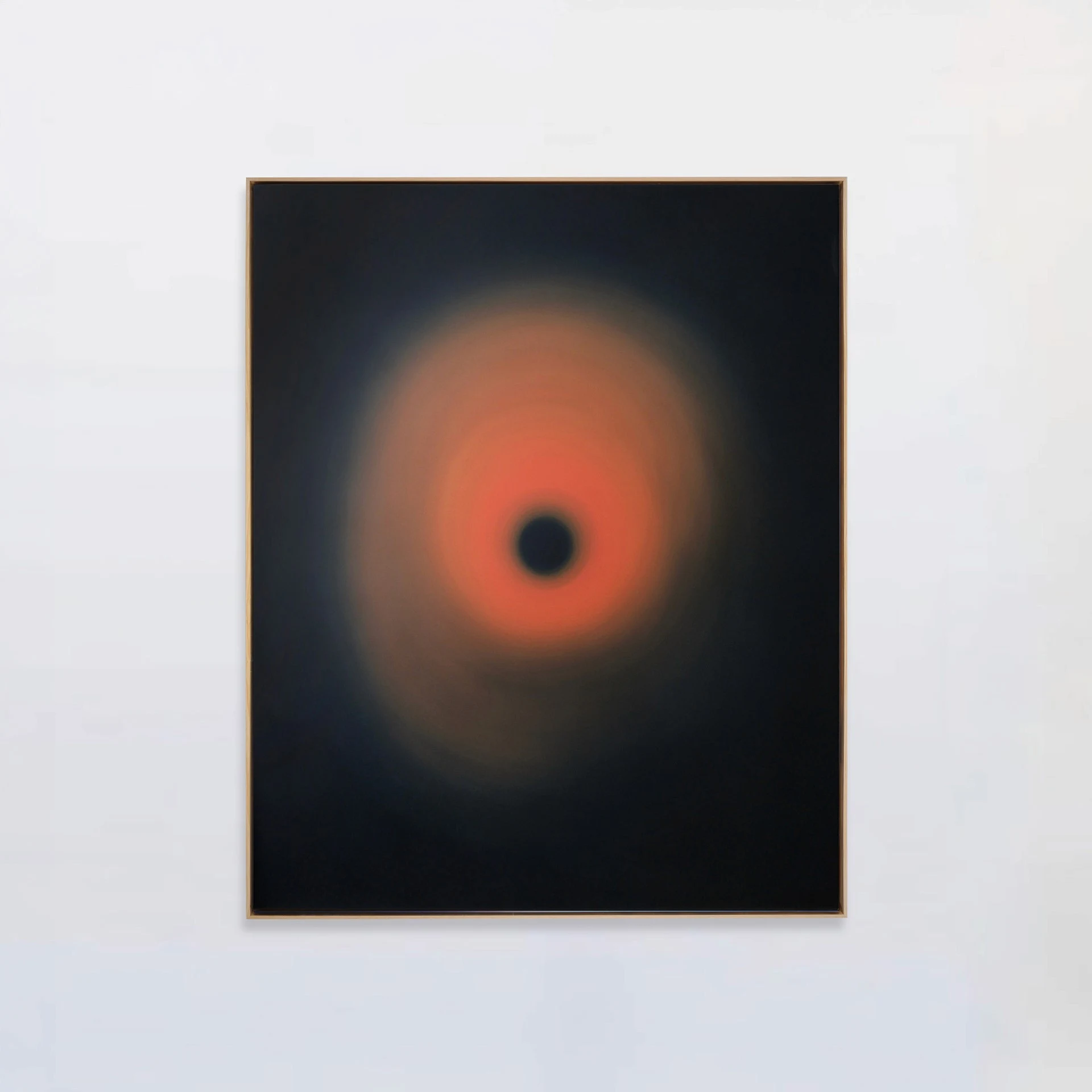 A dark panel holding a burning orange halo that radiates outward from a small black disc at its centre.